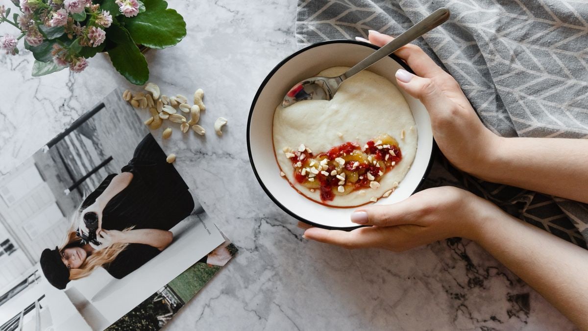 Top view of a yogurt bowl with nuts and berries on a marble table.